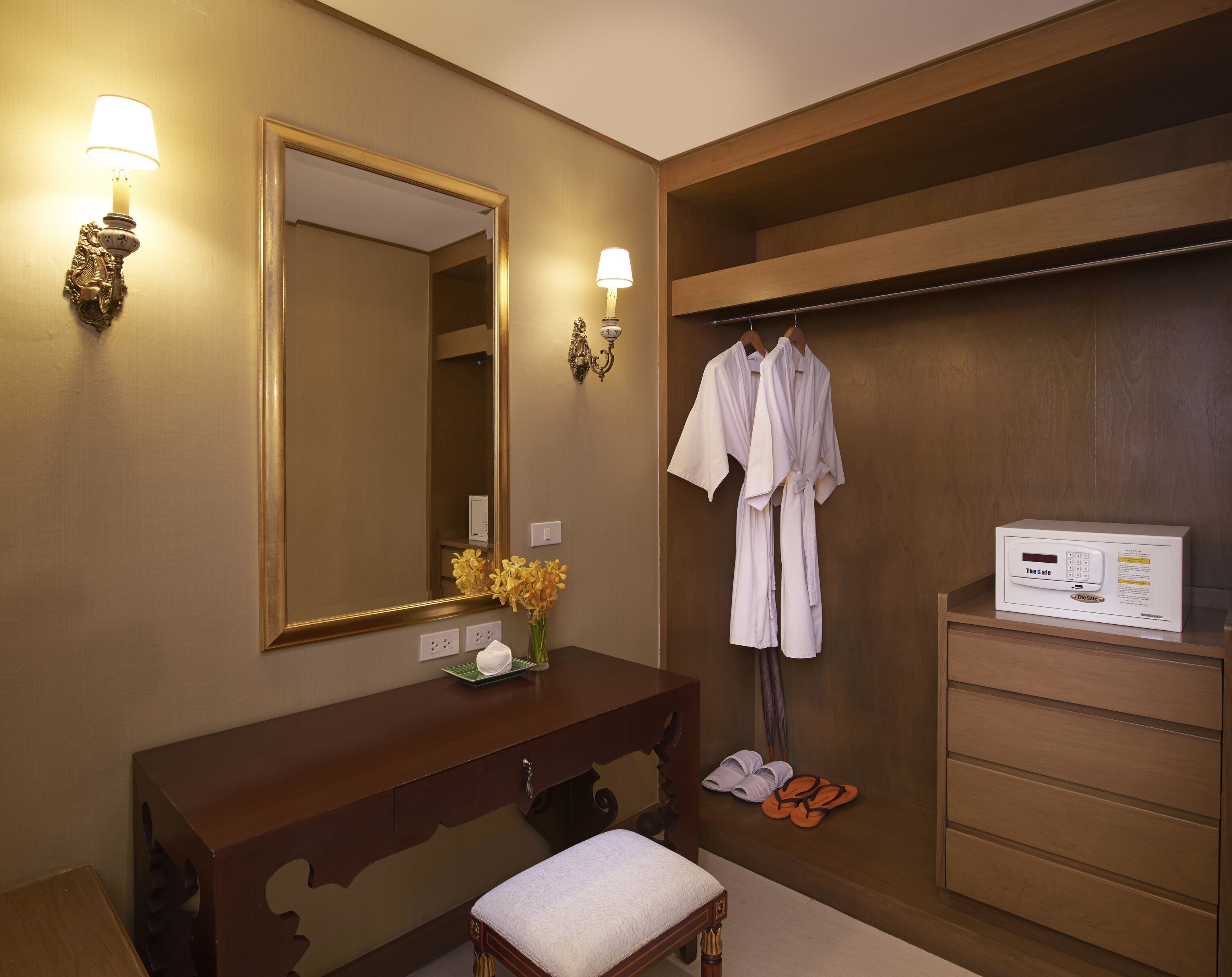 A hotel bathroom with a wooden vanity, a large mirror, a robe rack, and a TheSole control panel.
