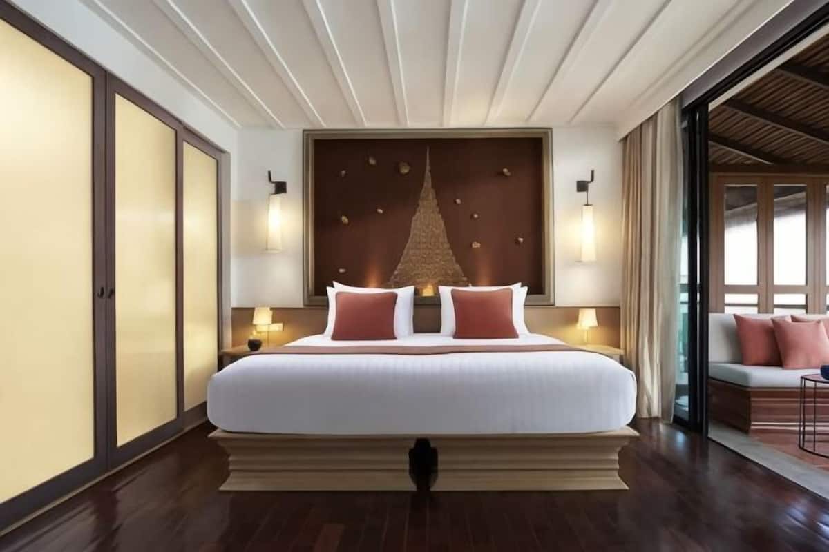 A large bed with a headboard, bedside lamps, and a view of a balcony.