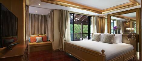 A spacious bedroom with a large bed, a television, and a balcony with a view of greenery.