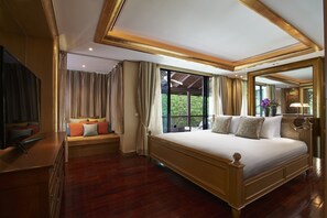 Un dormitorio amplio con una cama grande, televisión y balcón con vista a zonas verdes.