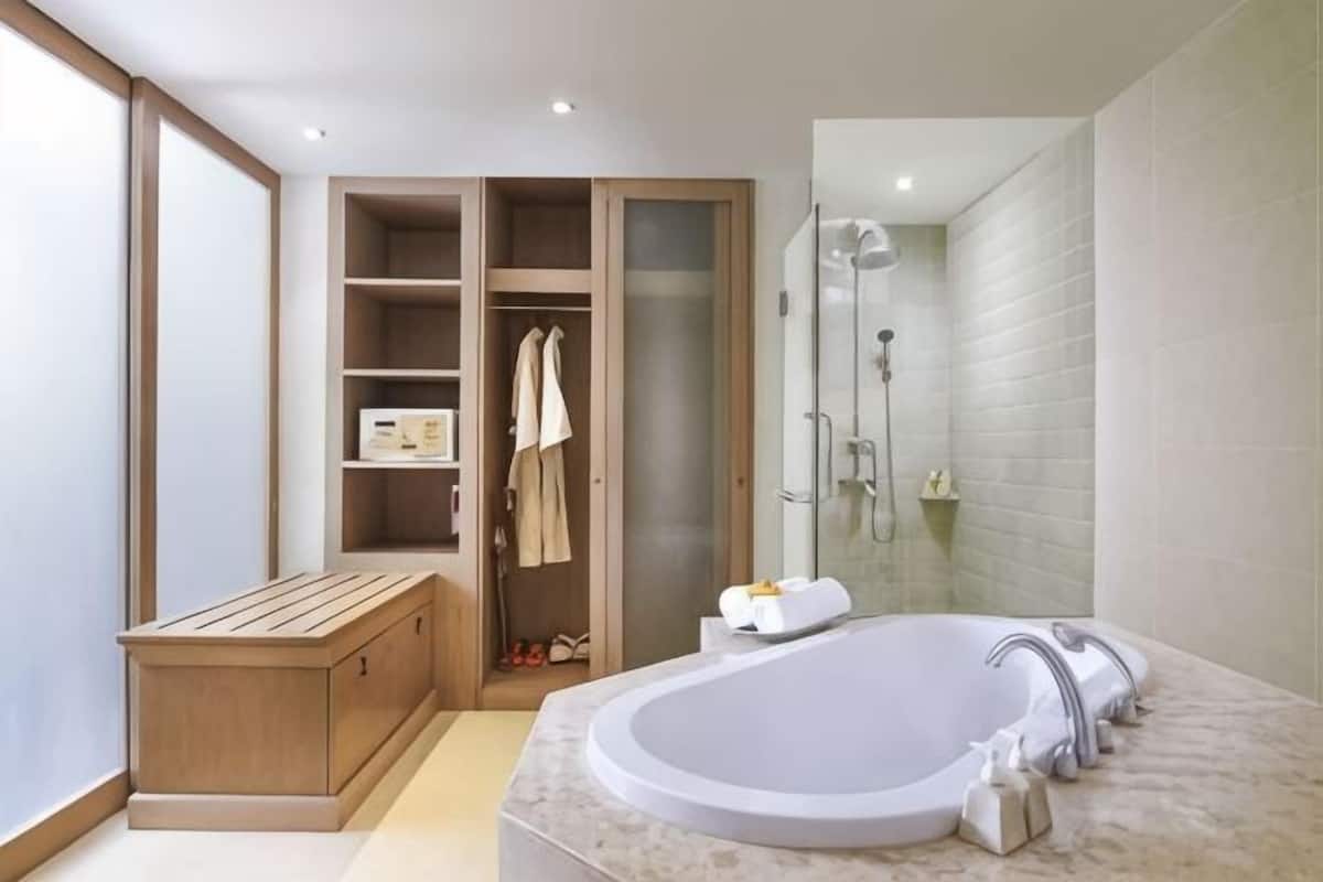 Un baño moderno con una bañera independiente, ducha a ras de suelo y tocador empotrado.