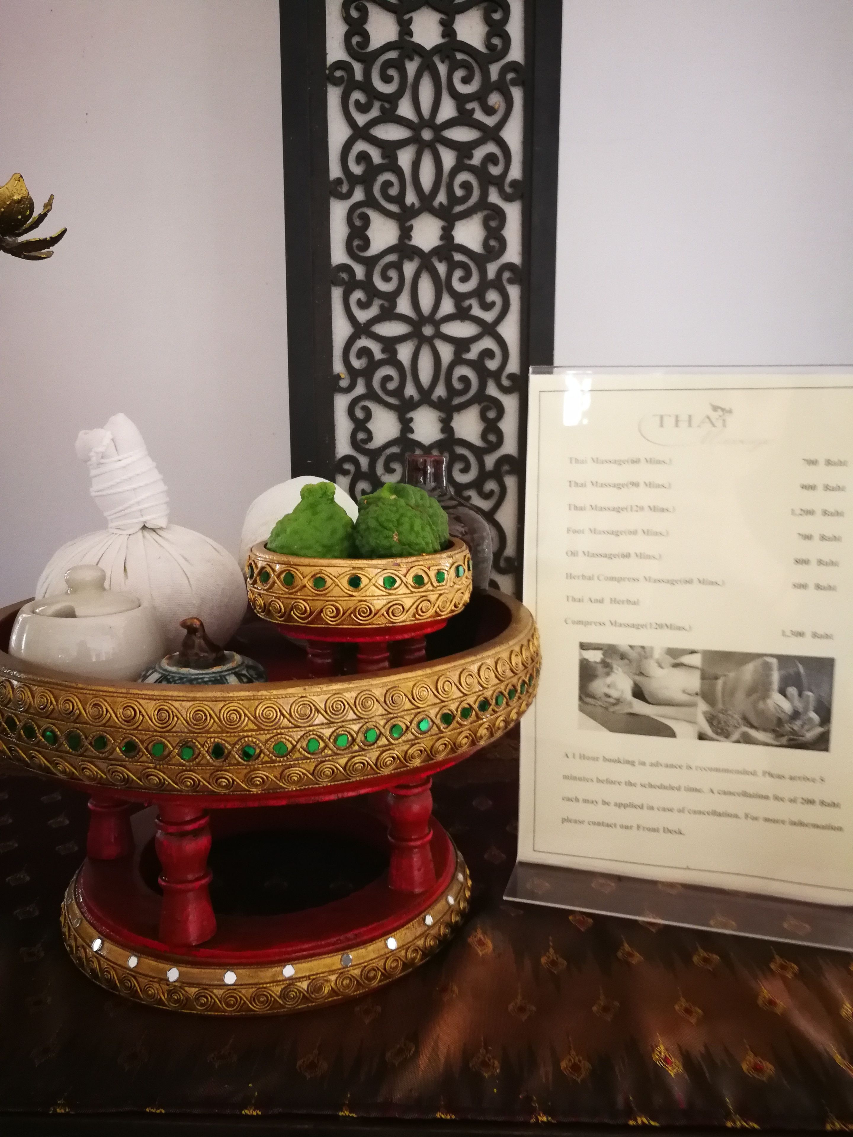 Una bandeja decorativa con una maceta blanca y un bol verde, un menú que enumera los servicios y un panel decorativo negro.