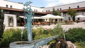 A courtyard with a fountain, outdoor seating, and a building with multiple windows.