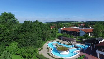 Un resort con piscina, rodeado de exuberante vegetación y un telón de fondo montañoso.