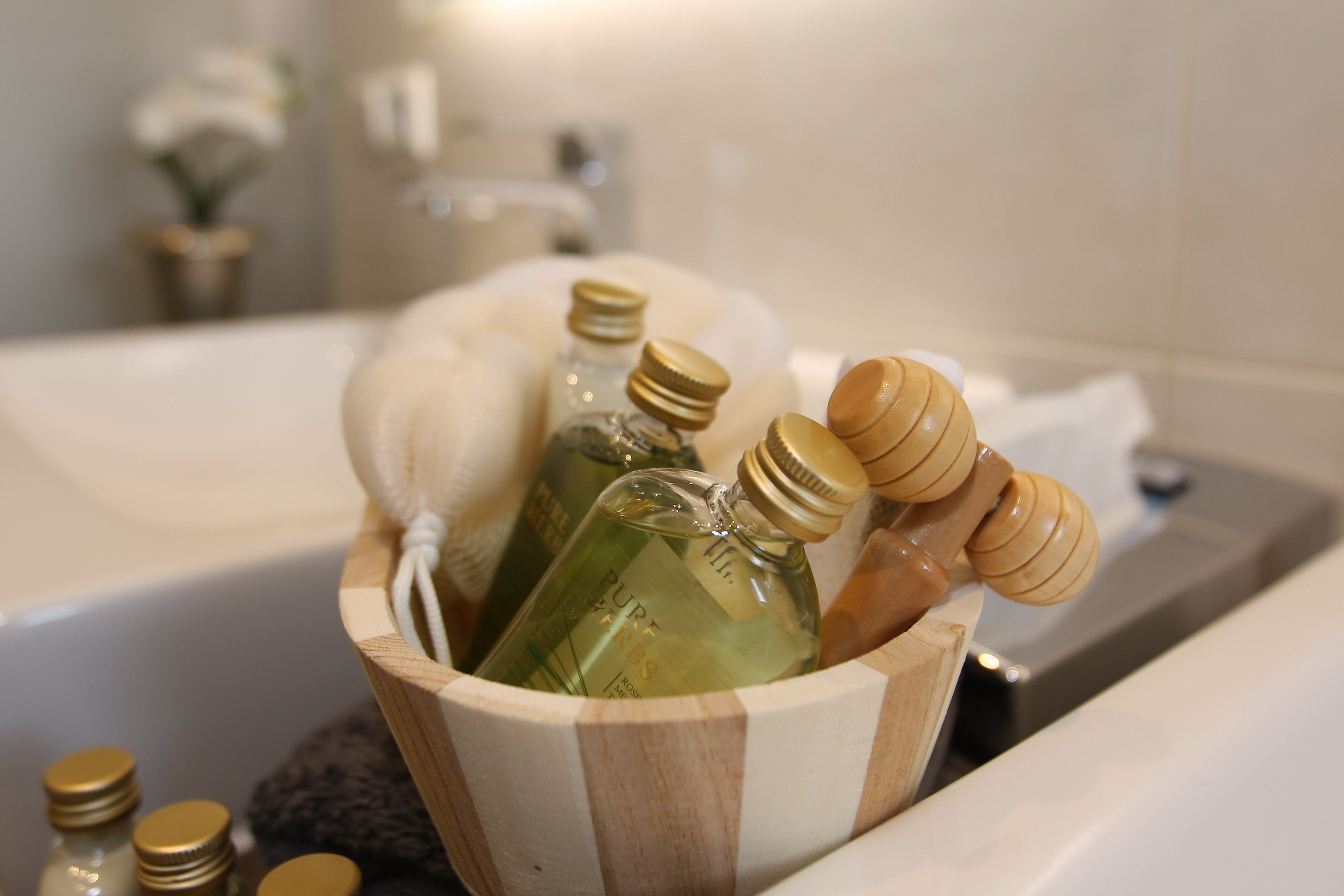 Un cubo de madera lleno de botellas y cucharas de madera en un baño.