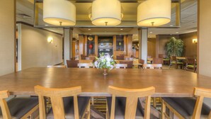 A conference room with a large wooden table, multiple chairs, and three large pendant lights. - Fairfield Inn & Suites by Marriott Laramie (Laramie)