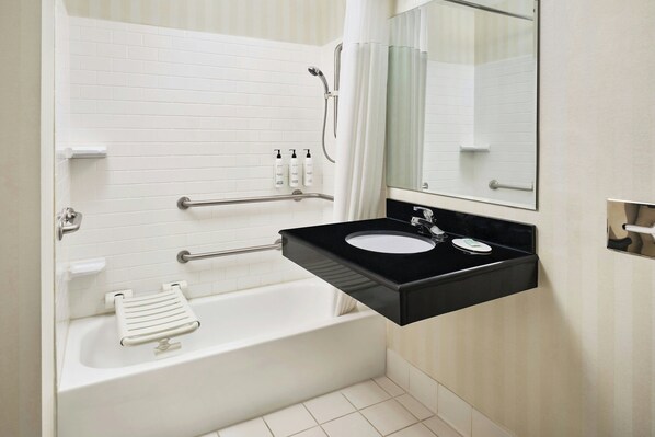 Un baño con una bañera blanca, un lavabo negro, un espejo y una ducha.