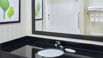 Un baño con lavamanos de encimera negro, espejo y ducha.