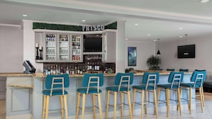 A bar area with a 'FRISCO' sign, bar stools, and a variety of bottles and glasses. - Hilton Garden Inn Frisco (Frisco)