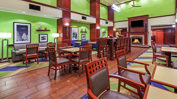 A spacious hotel lobby with multiple seating areas, a fireplace, and artwork on the walls. - Hampton Inn & Suites Tulsa North/Owasso (Owasso)