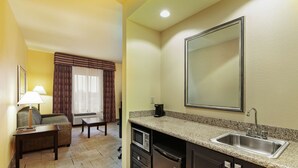 A compact kitchen with a microwave, refrigerator, and sink. There is a small dining area with a table and chairs, and a sofa. - Hampton Inn & Suites Tulsa North/Owasso (Owasso)