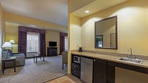 A compact hotel room with a kitchenette, a sofa, a TV, and a dining area. - Hampton Inn & Suites Tulsa North/Owasso (Owasso)