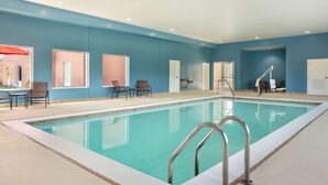 Une piscine à l’intérieur d’un bleu clair, entourée d’un mur bleu et dotée d’une échelle en métal.
