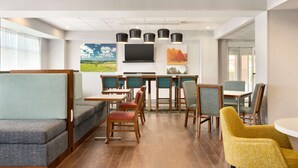 Un hall d’hôtel moderne, doté d’espaces aménagés avec des sièges, d’un bar et d’œuvres d’art accrochées aux murs.