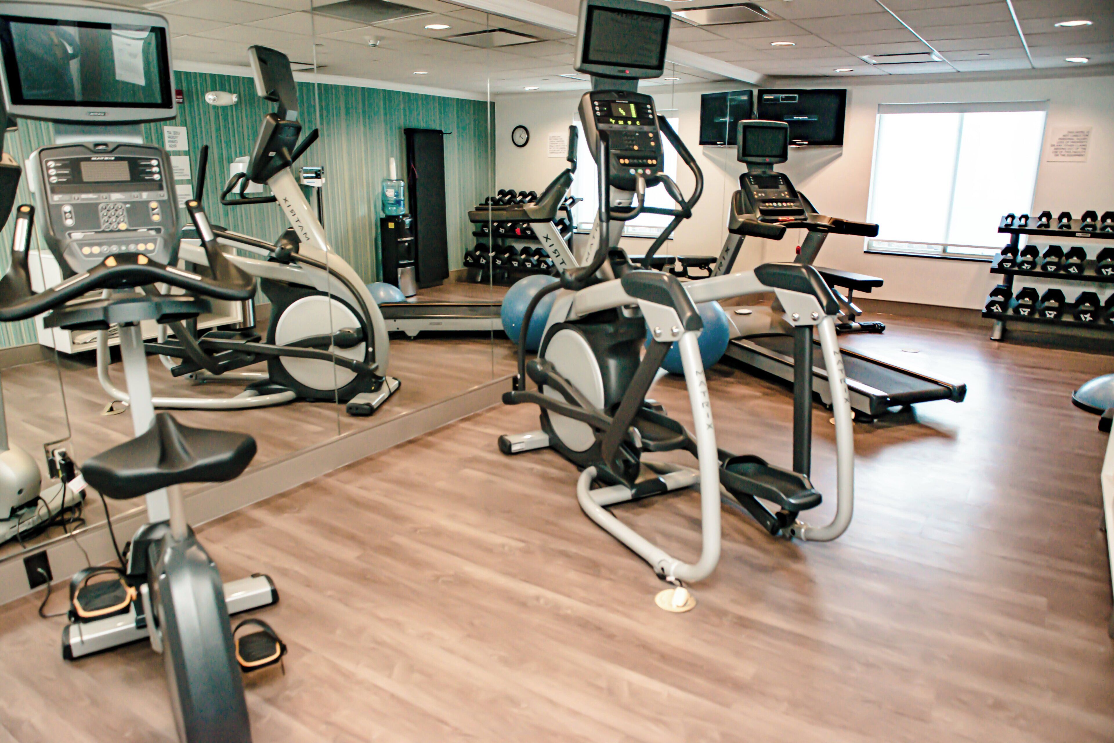 Een sportschool met diverse trainingsapparaten, zoals loopbanden, hometrainers en gewichten.