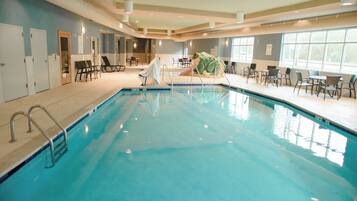 An indoor swimming pool with a slide, lounge chairs, and a frog statue.