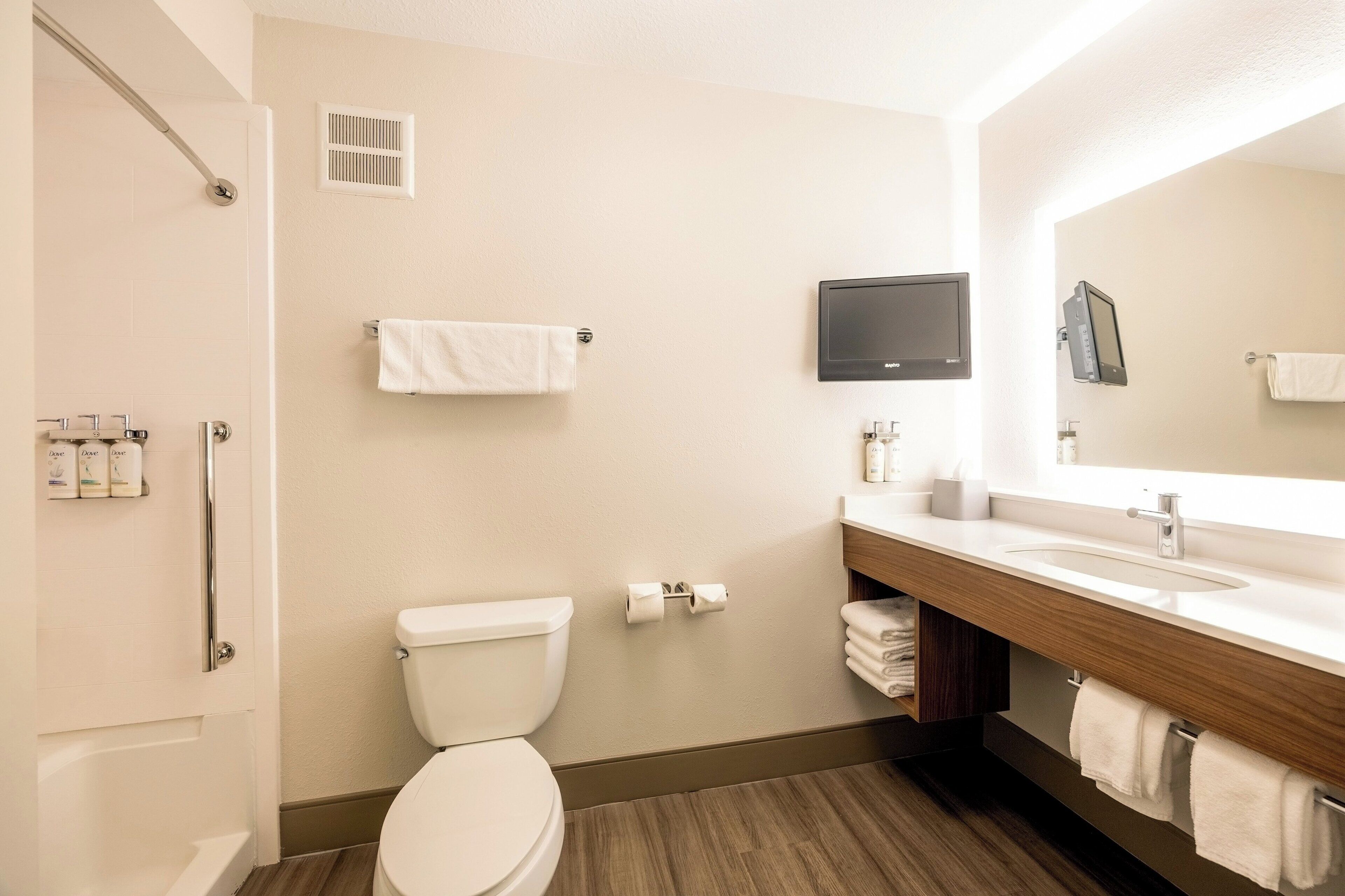 A modern bathroom with a toilet, sink, mirror, and shower.