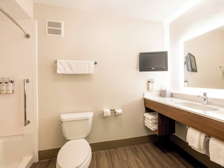 A modern bathroom with a toilet, sink, mirror, and shower.