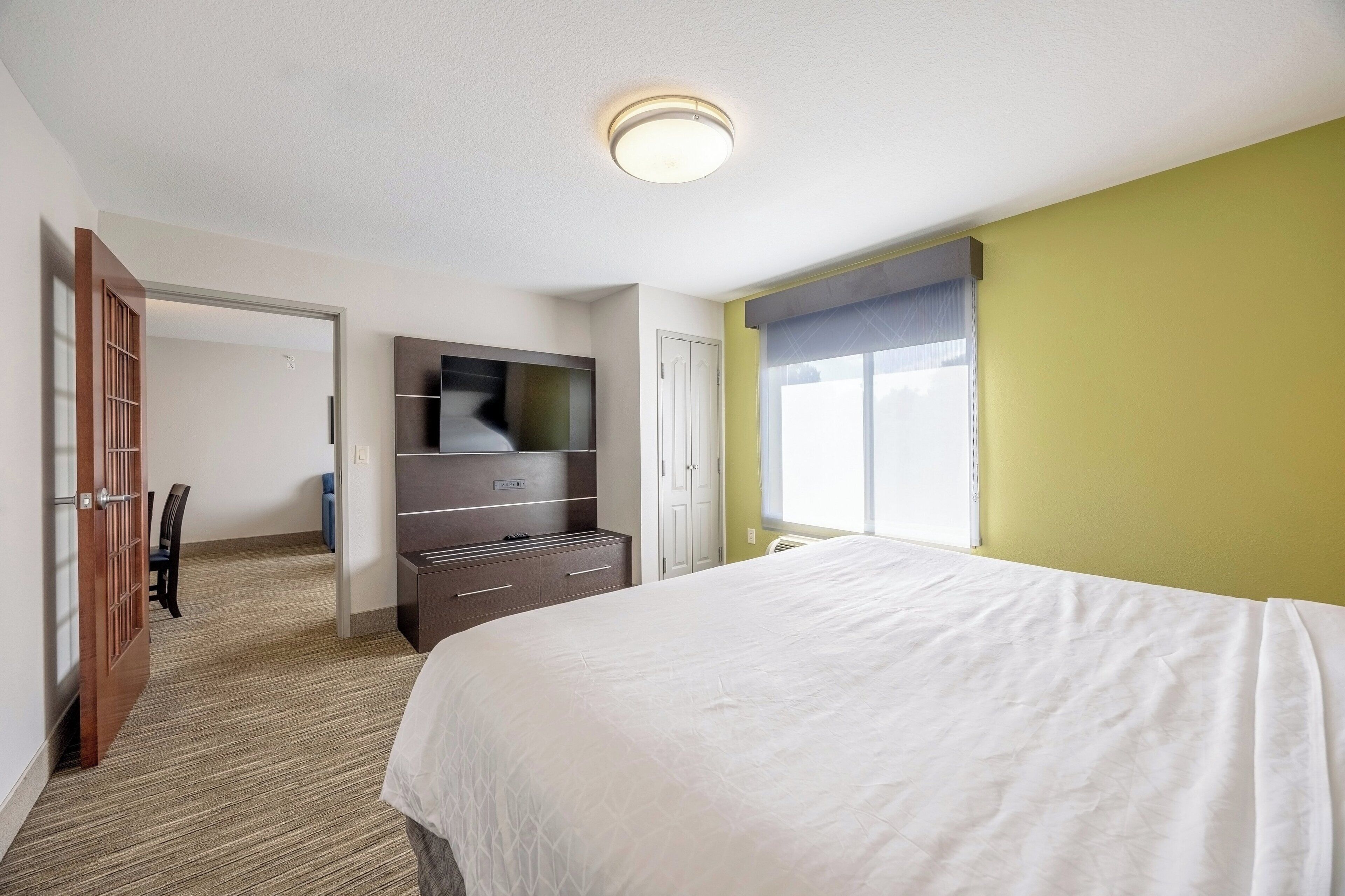 Ein Hotelzimmer mit einem Bett, einem Kleiderschrank, einem Schreibtisch und einem Fenster.