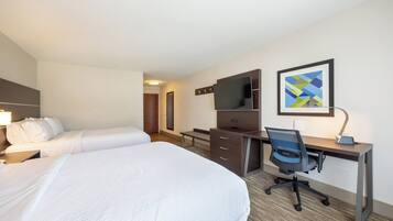 A hotel room with a large bed, a desk with a chair, a flat-screen TV, and a framed abstract art piece on the wall.