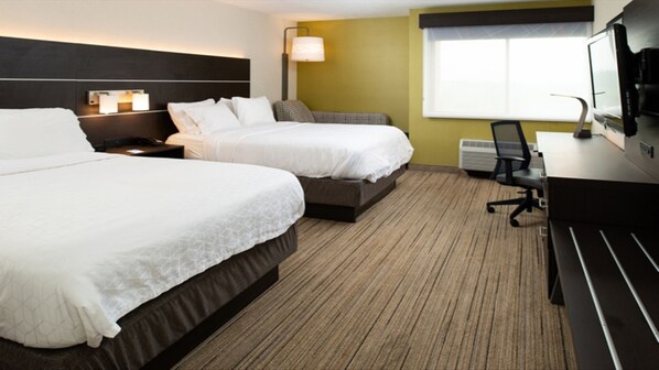 A hotel room with two beds, a desk, a chair, a TV, and a window.