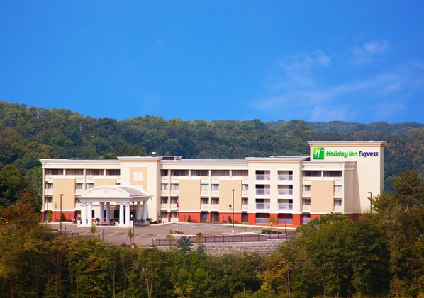 A Holiday Inn Express hotel with a central courtyard, multiple floors, and a mountainous backdrop. - Holiday Inn Express West Cincinnati by IHG (Cincinnati)
