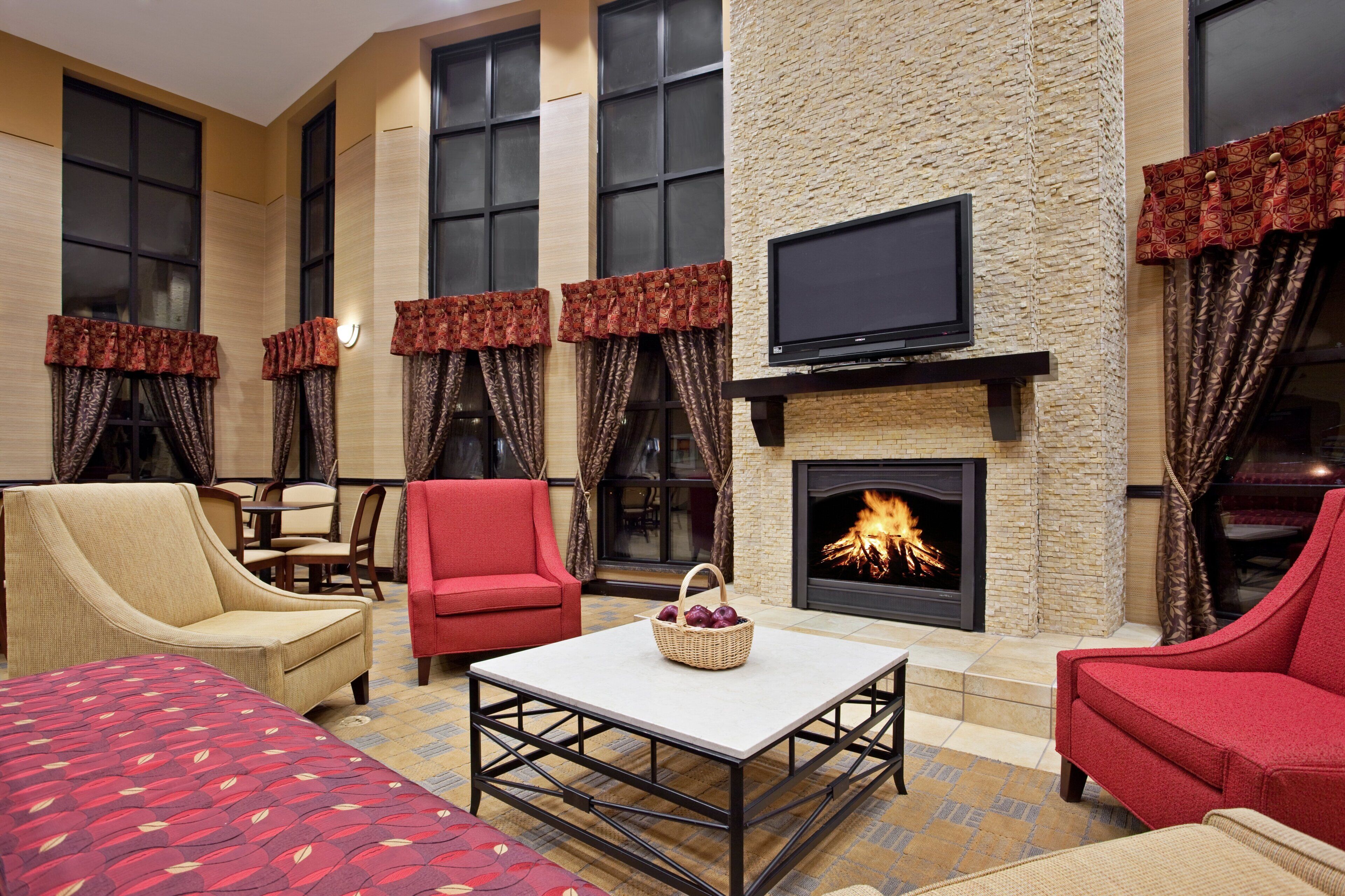 A hotel lounge with a fireplace, multiple seating options, and a flat-screen TV.