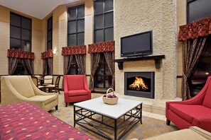 A hotel lounge with a fireplace, multiple seating options, and a flat-screen TV. - Holiday Inn Express West Cincinnati by IHG (Cincinnati)