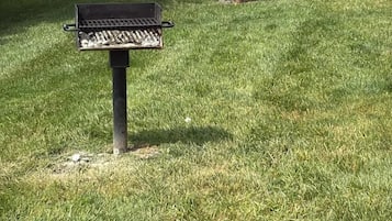 A grassy area with a metal grill and a mailbox.