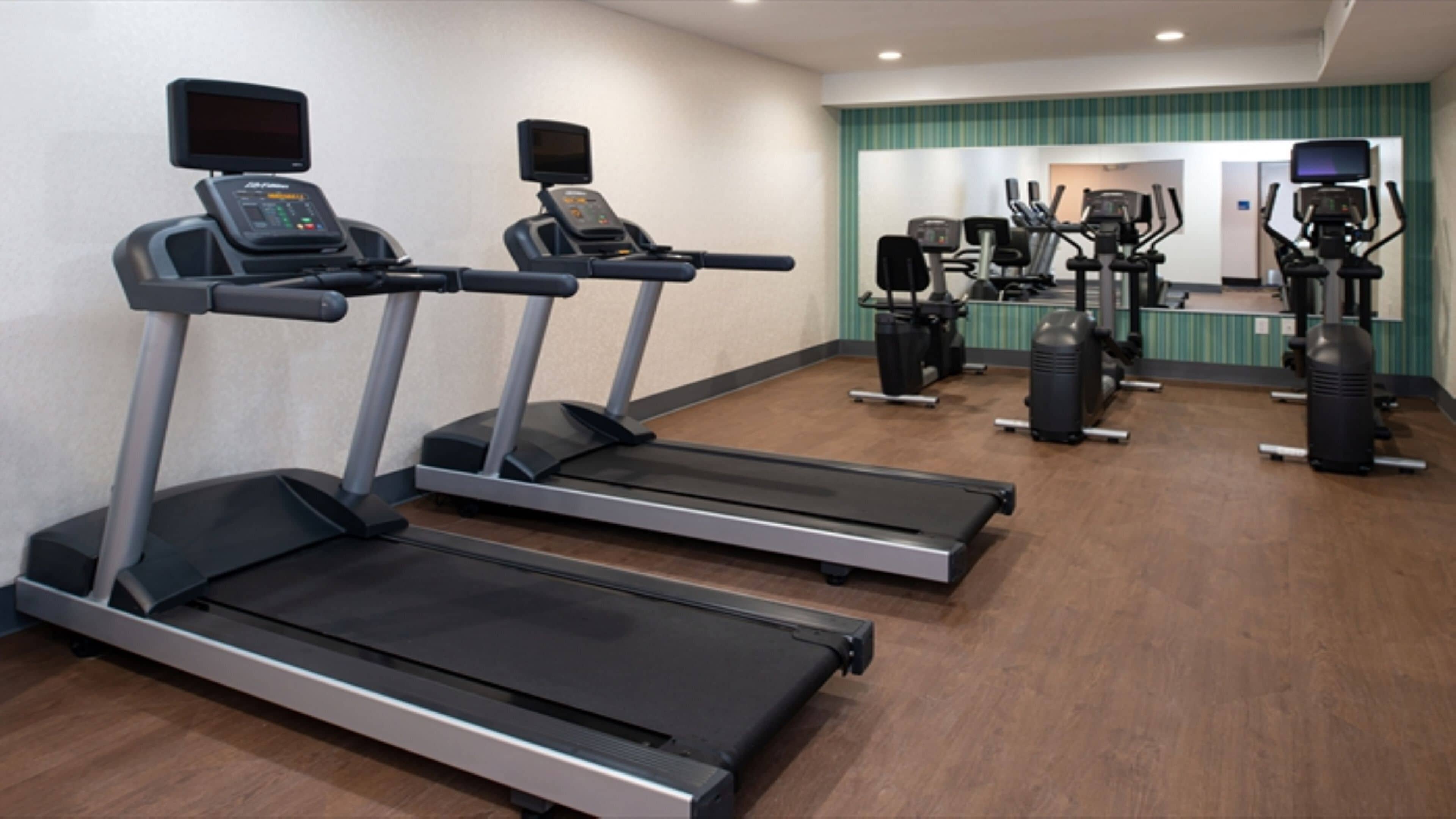 A fitness center with treadmills, elliptical machines, and weight equipment.