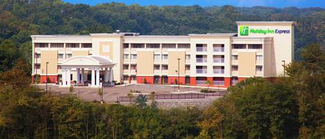 A Holiday Inn Express hotel with a central courtyard, multiple floors, and a forested backdrop.