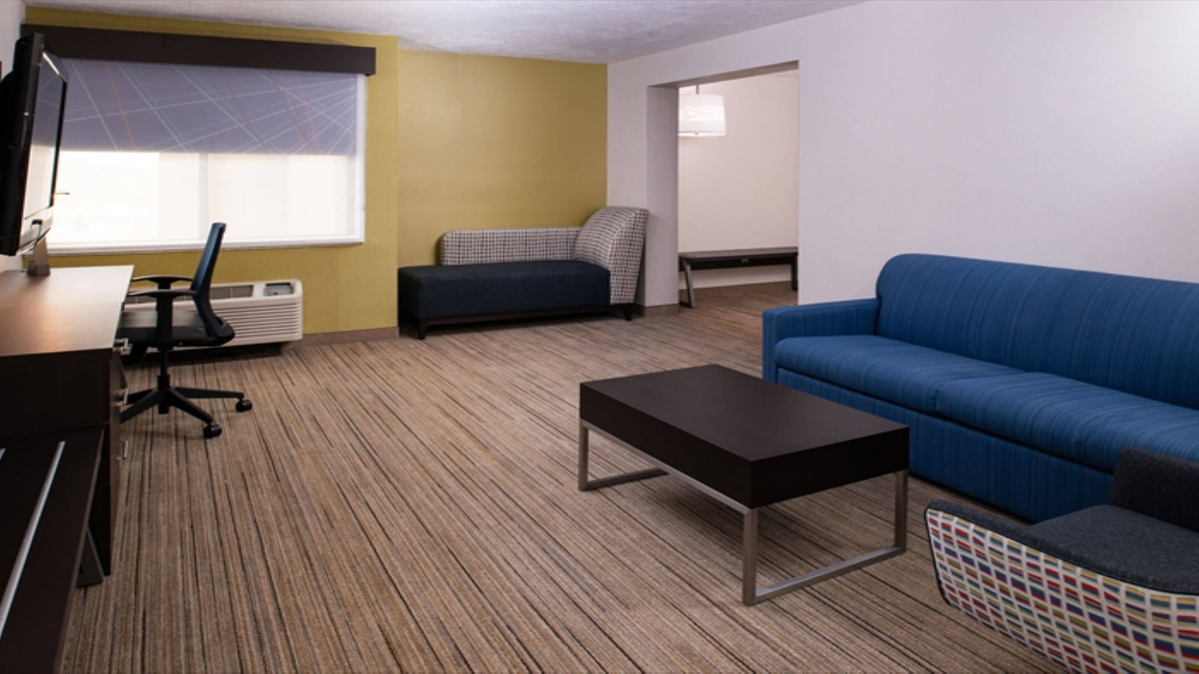 A furnished living room with a sofa, a small table, a chair, and a television.