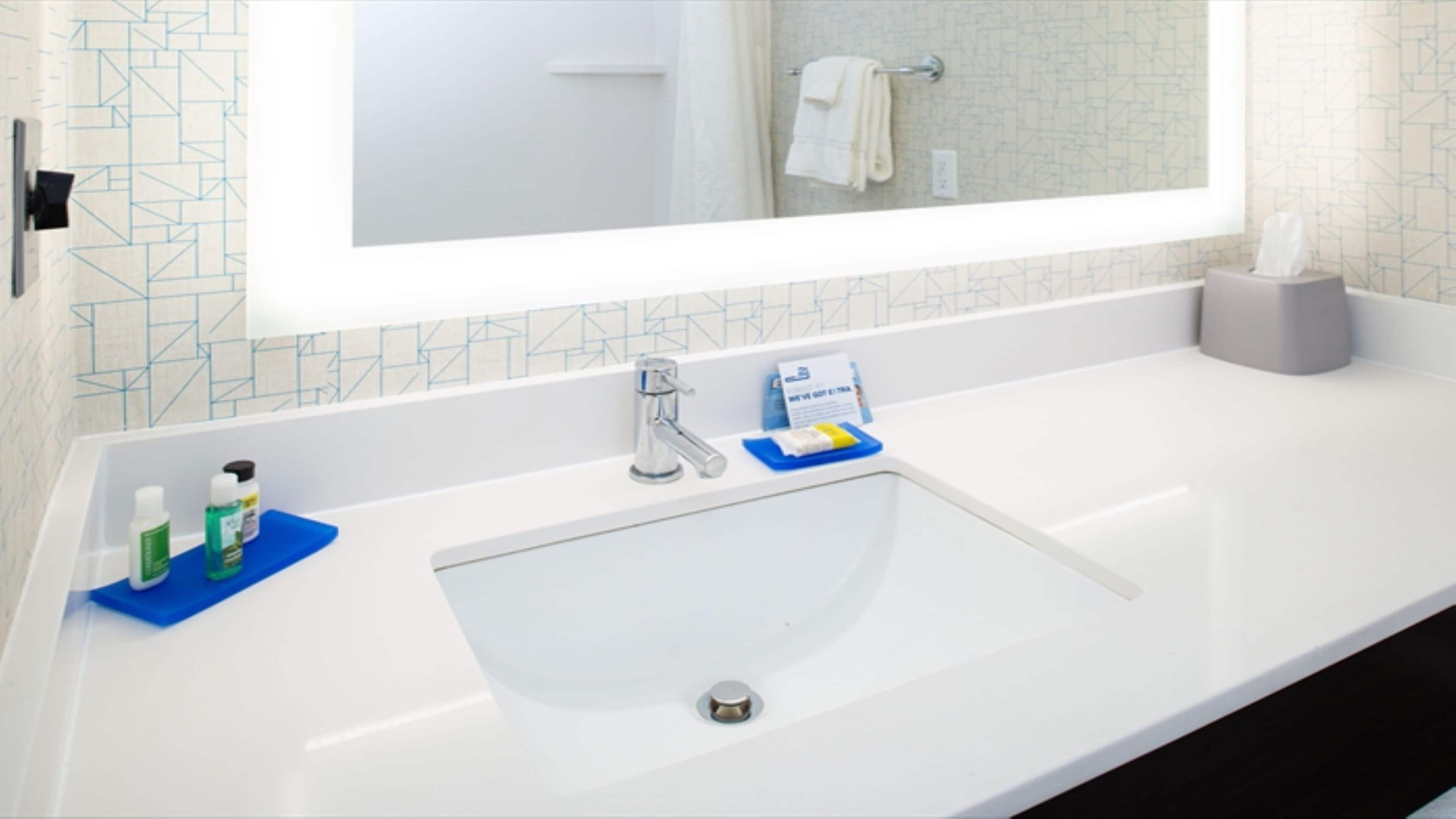 A bathroom with a white sink, a mirror, and a towel rack.