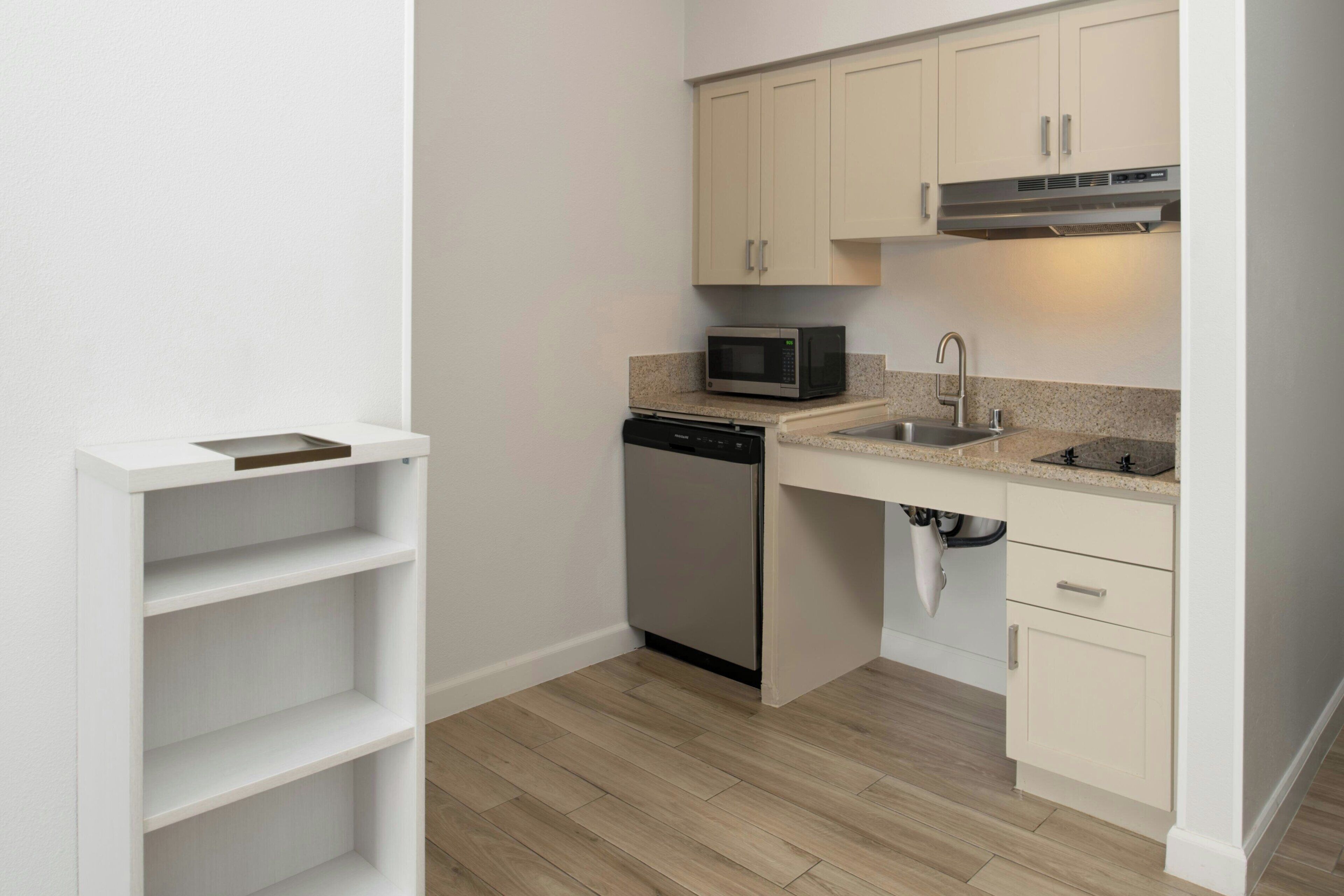 A compact kitchen with white cabinets, a microwave, a dishwasher, and a sink.