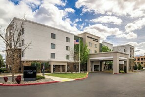 A modern hotel with a flat roof, a sign indicating it's a TownePlace Suites by Marriott, and a parking lot.