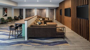 A modern lobby with a reception desk, seating area, and wall-mounted televisions. - TownePlace Suites by Marriott Reno (Reno)