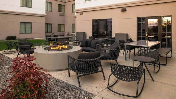 A patio area with outdoor seating, a fire pit, and a building with multiple windows. - TownePlace Suites by Marriott Reno (Reno)