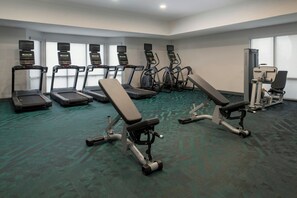 A gym with treadmills, elliptical machines, and weight benches.