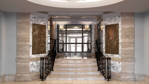 A grand staircase with marble walls and black iron railings leading to a bright, well-lit interior space. - The Westin Book Cadillac Detroit (Detroit)