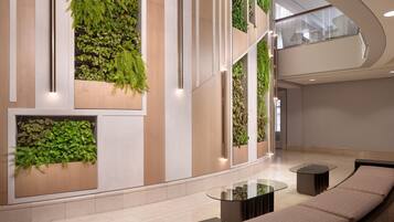 Un hall d’entrée moderne agrémenté de jardins verticaux, d’un canapé aux lignes courbes et d’une table basse en verre.