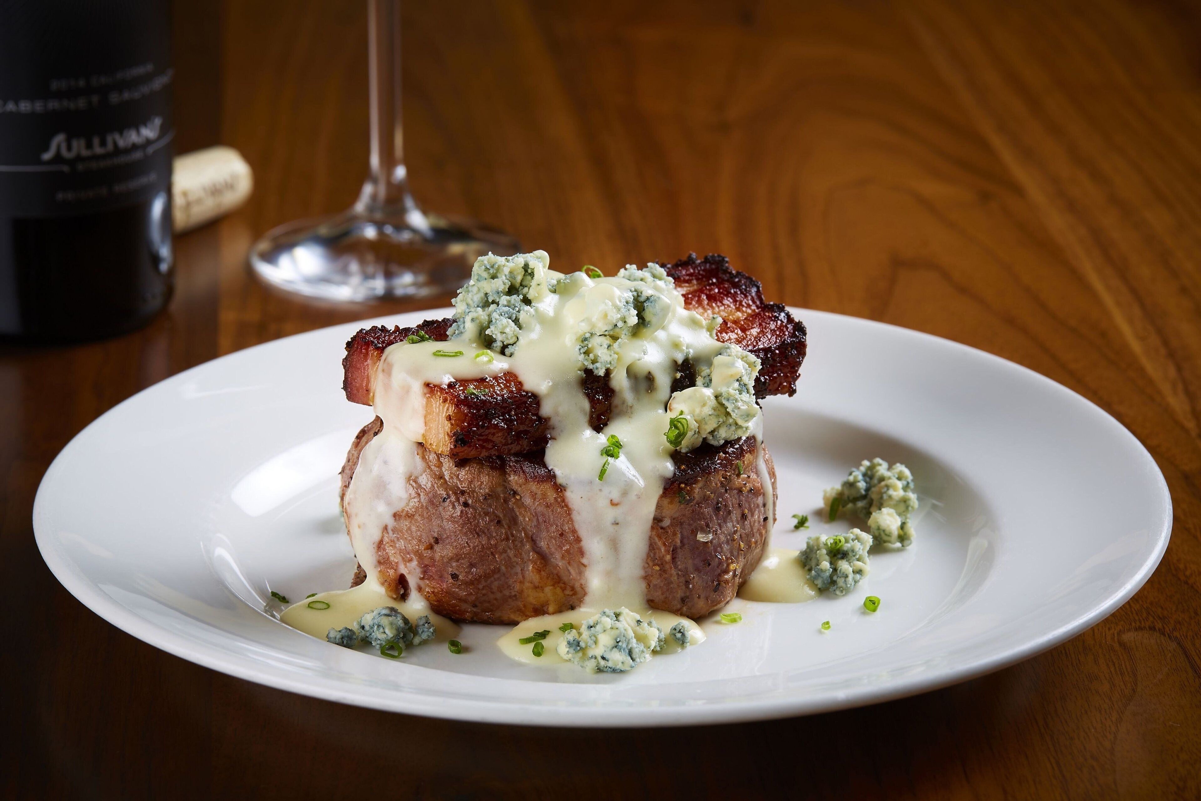 A plate of food with a bottle and glass in the background.