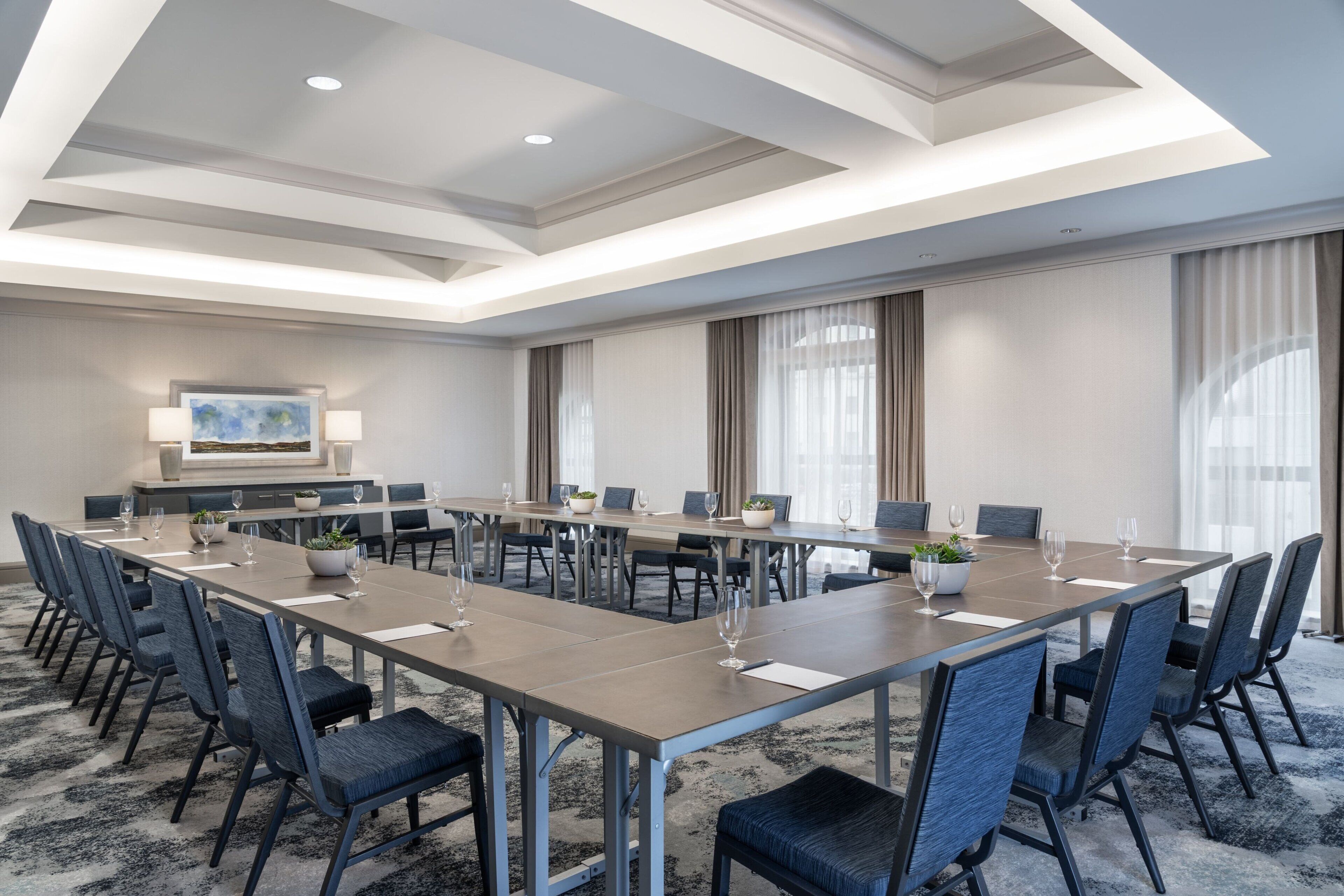 A conference room with a long table, chairs, and a television screen.