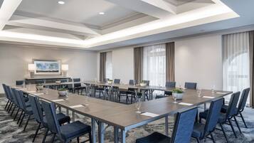 A conference room with a long table, chairs, and a television screen.