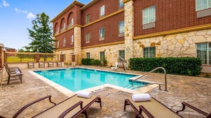 Relax by the pool surrounded by lush surroundings and lounge chairs.