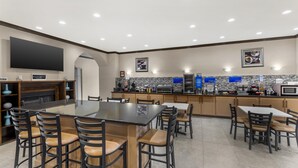 A modern kitchen with a large island, bar stools, and a flat-screen TV. - Best Western Red River Inn & Suites (Thackerville)