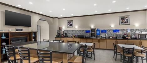 A modern kitchen with a large island, bar stools, and a flat-screen TV.