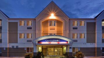 Un hotel con una entrada destacada, un cartel que dice 'CANDLEWOOD SUITES' y un estacionamiento con espacios reservados para discapacitados.