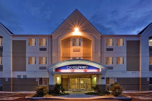 Un hôtel doté d’une entrée imposante, d’une enseigne indiquant « CANDLEWOOD SUITES » et d’un parking comprenant des places réservées aux personnes handicapées.