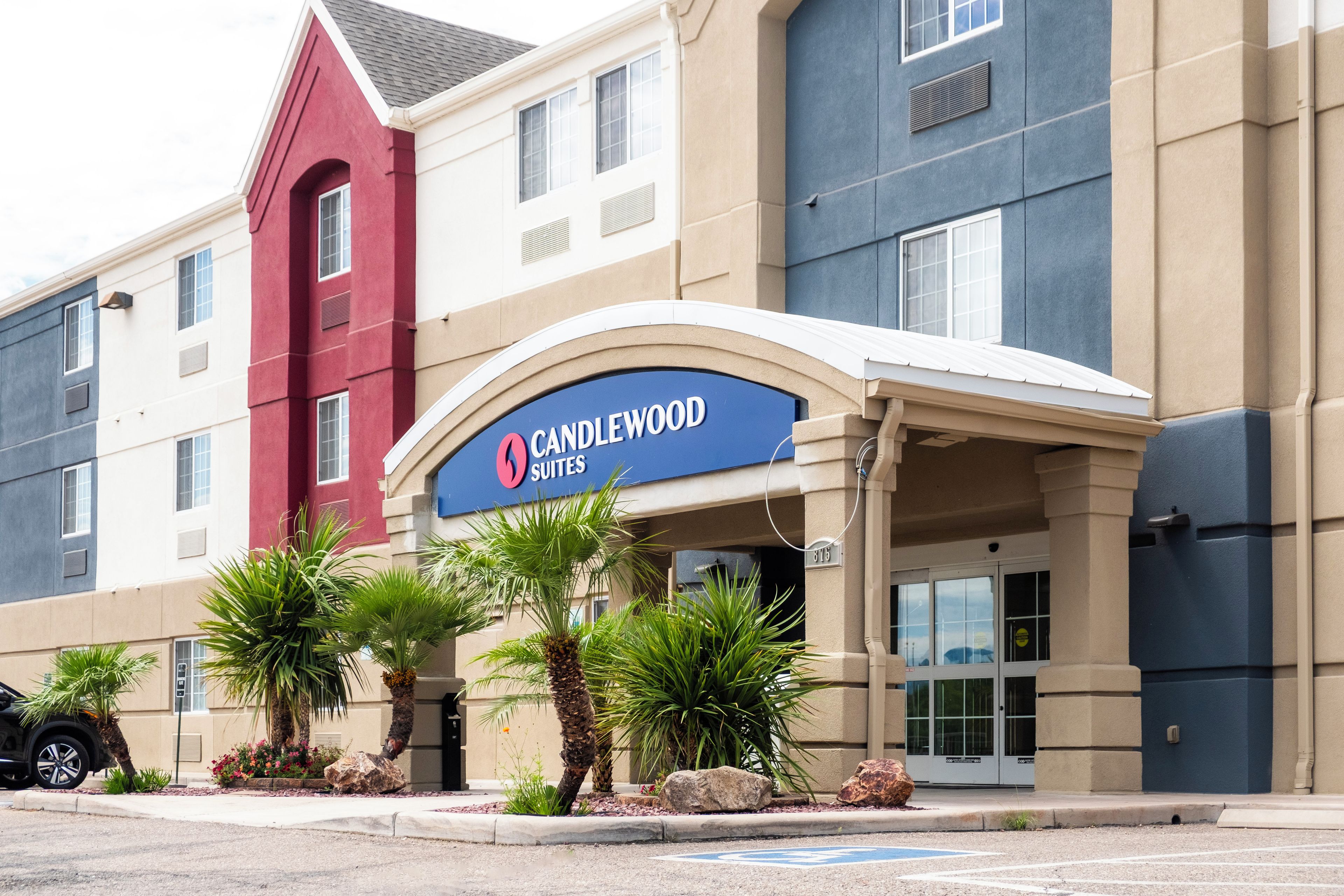 Entrada de un hotel con un cartel que dice 'CANDLEWOOD SUITES' y un corredor cubierto.