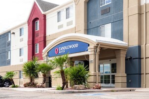 Entrada de un hotel con un cartel que dice 'CANDLEWOOD SUITES' y un corredor cubierto.